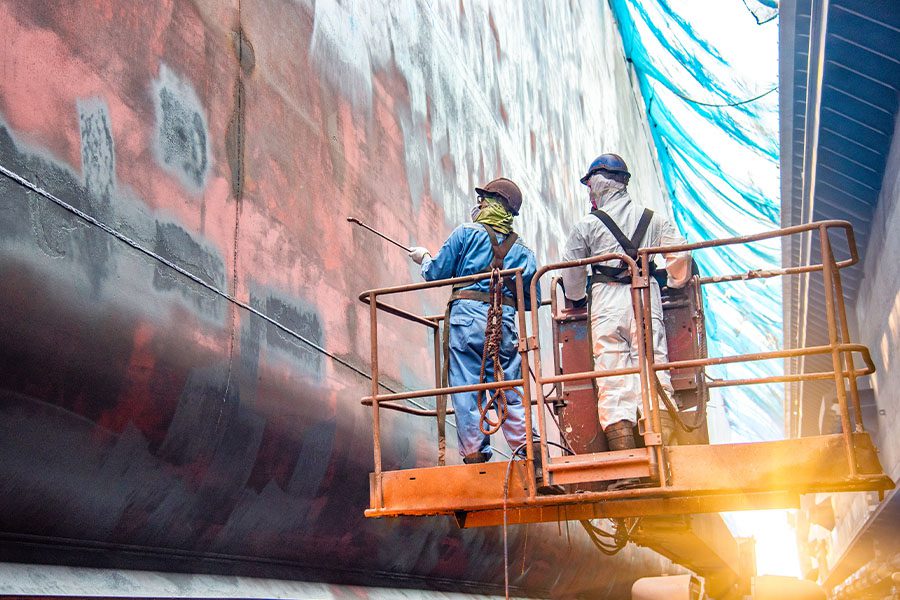 Marine Contractor Insurance - Steel Basket Carrying Workers by Crane to Clean and Repair a Ship