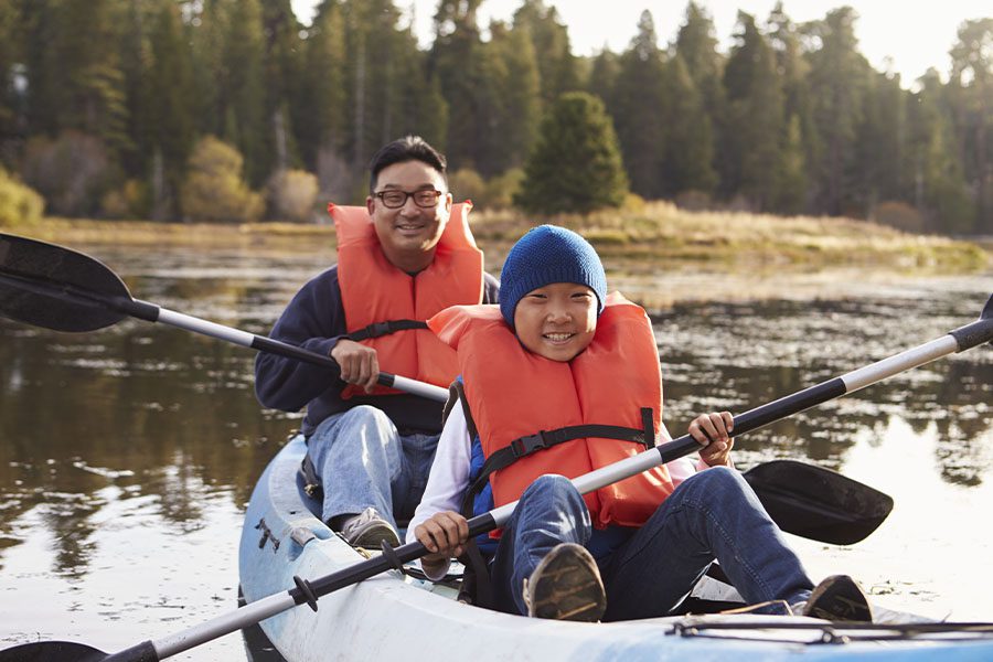 Employee Benefits - Portrait of a Father and Son Kayaking on a Rural Lake at Dusk