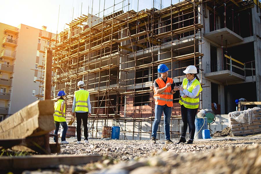 Business Insurance - Four Construction Workers Having Meeting at a Construction Site on a Sunny Day