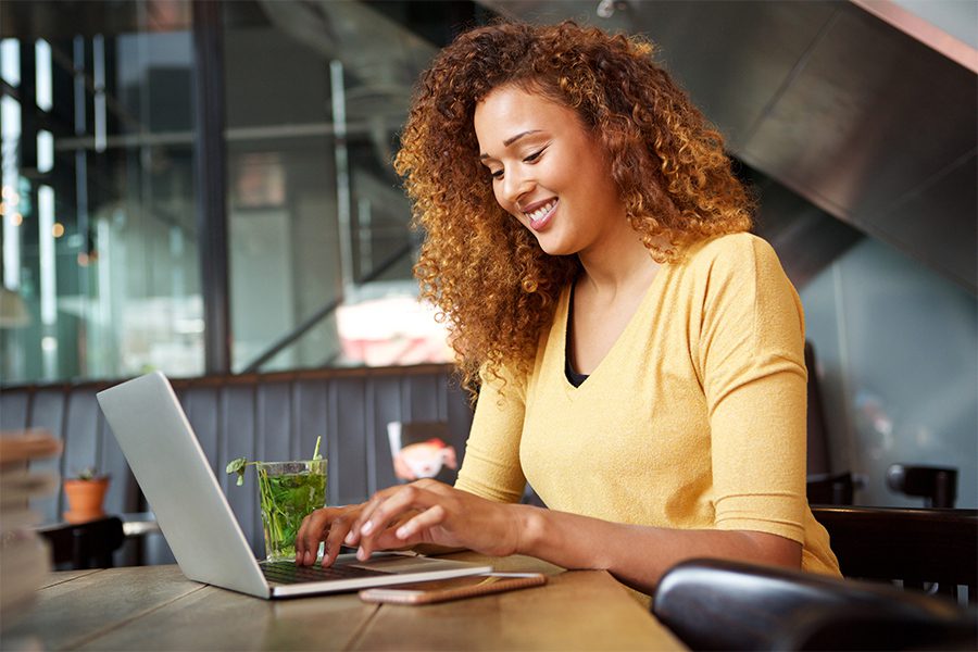 Blog - Young Woman Smiling at Her Laptop While Sitting at a Desk